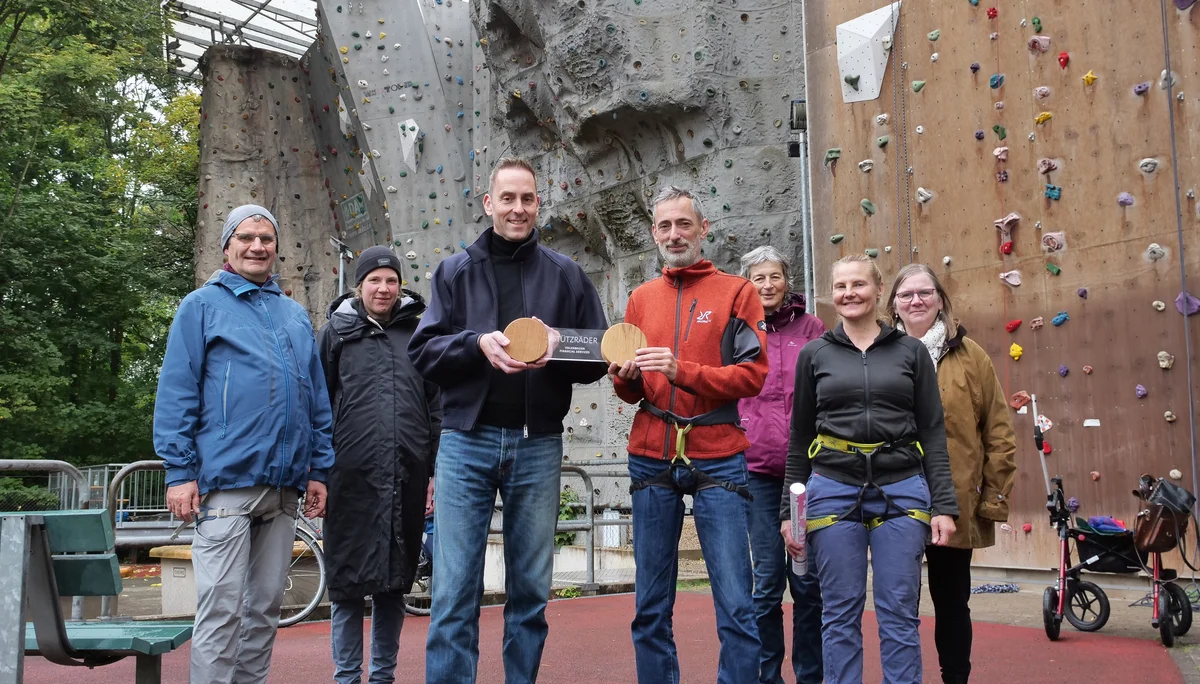 Übergabe der Stützräder-Skulptur an die EWI. Von links nach rechts: Ralf Hartzsch, Ilka Töniges, Arne Puls, Stefan Burek, Christiane Podlech, Vanessa Burek und Gabriele Flammann. Im Hintergrund die Kletterwand in der Güldenstraße. | © VW Financial Services