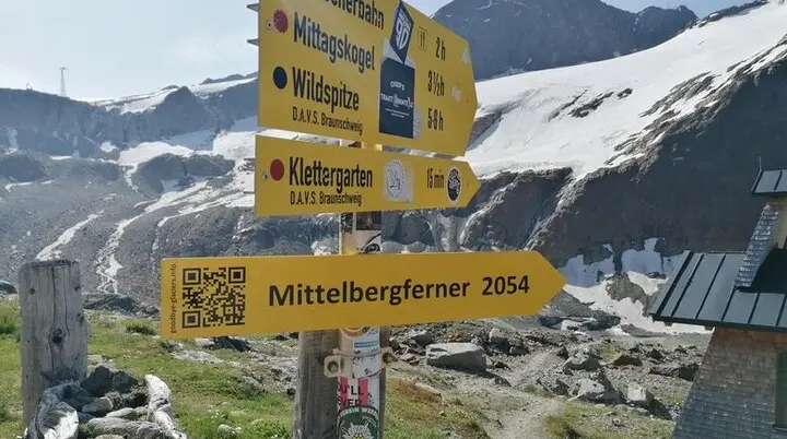 Der Wegweiser neben der Braunschweiger Hütte zeigt auf den Mittelbergferner und dessen prognostizierten Rückgang bis 2054. Ein QR-Code verweist auf goodbye-glaciers.info. | © Günter Gehrke