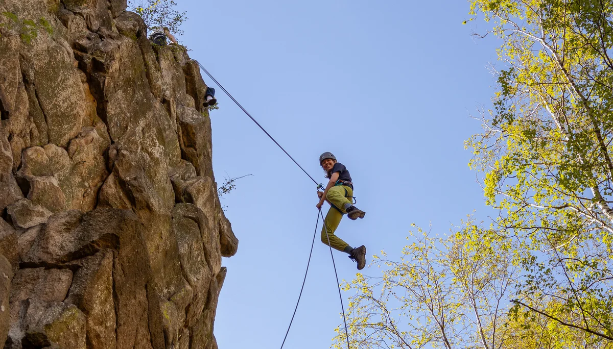 Eine Person seilt sich von einem Felskopf ab und hat sichtlich Spaß dabei | © Daniel Schmid