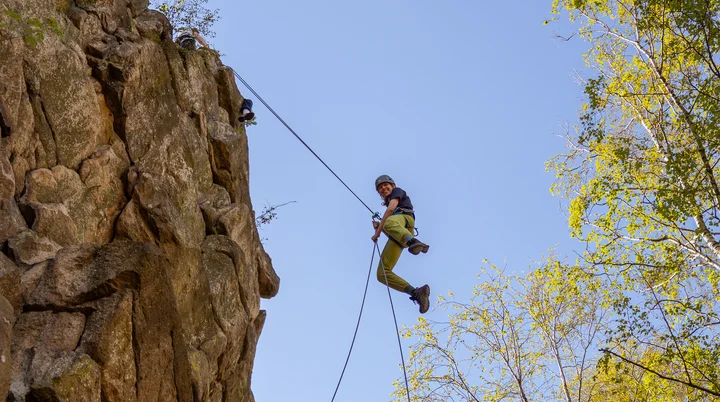 Eine Person seilt sich von einem Felskopf ab und hat sichtlich Spaß dabei | © Daniel Schmid