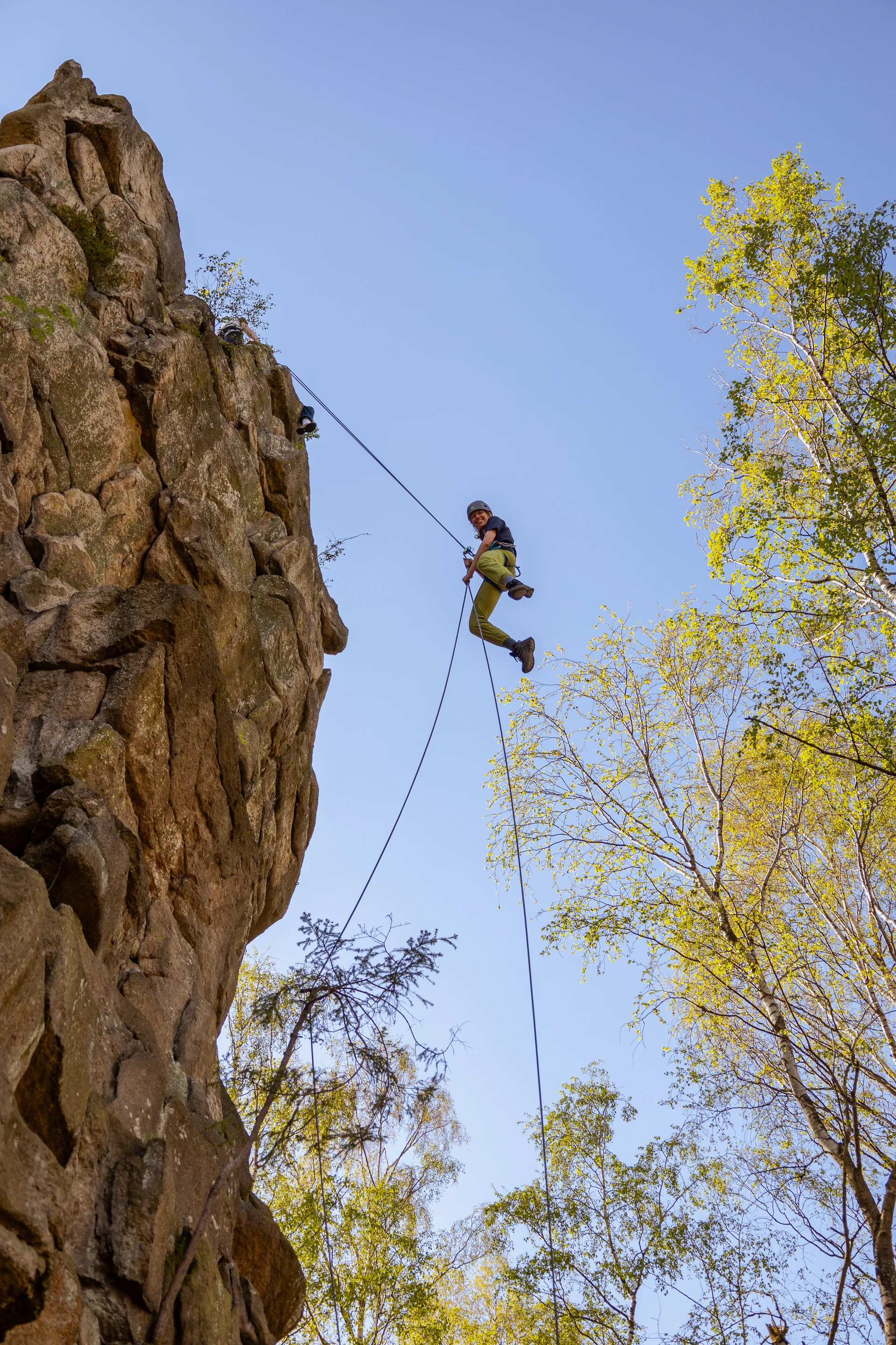 Eine Person seilt sich von einem Felskopf ab und hat sichtlich Spaß dabei | © Daniel Schmid