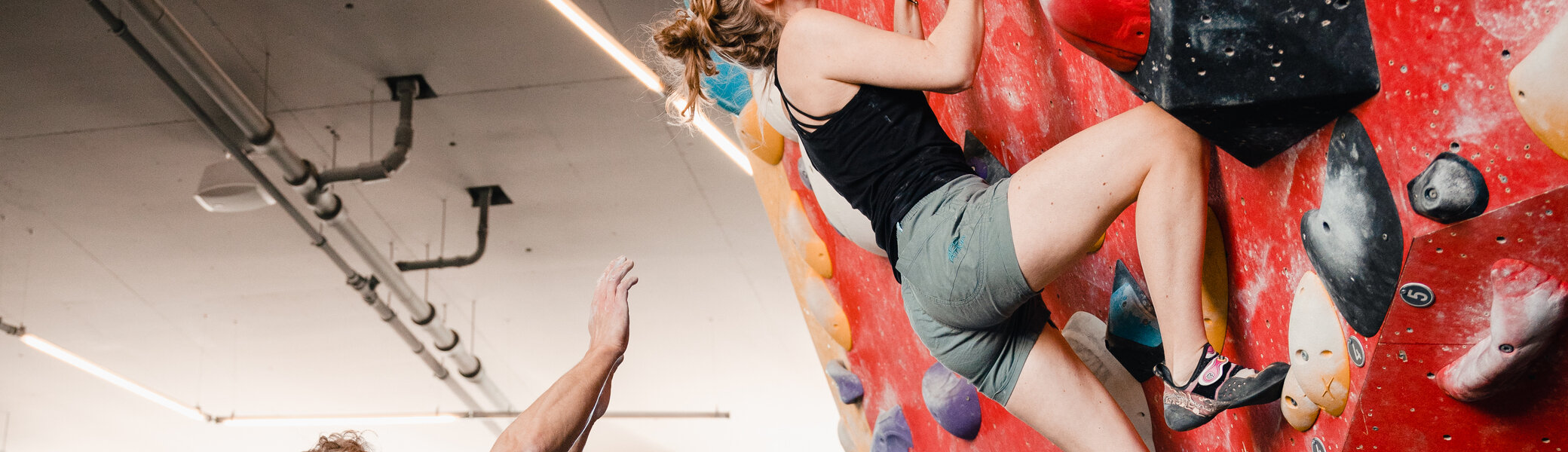 Eine Frau klettert in einer Kletterhalle, ihr Partner sichert sie. | © DAV/Marisa Koch