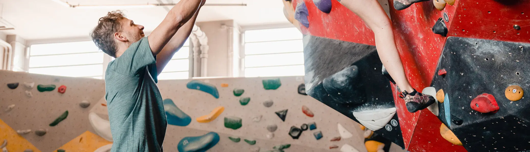 Eine Frau klettert in einer Kletterhalle, ihr Partner sichert sie. | © DAV/Marisa Koch