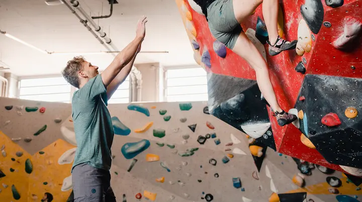 Eine Frau klettert in einer Kletterhalle, ihr Partner sichert sie. | © DAV/Marisa Koch