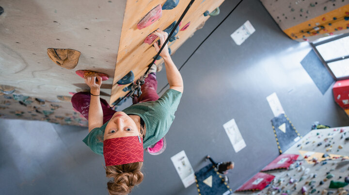 Eine Frau klettert in einer Kletterhalle, ihr Partner sichert sie. | © DAV/Marisa Koch